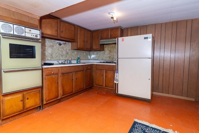 5375 Fullerton Dr, Columbus, OH 43232 - kitchen featuring white appliances, under cabinet range hood, brown cabinets, light countertops, and backsplash