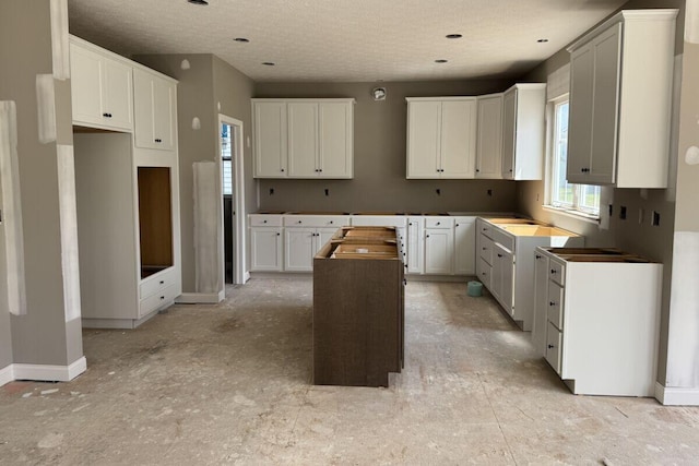 6938 Stillhouse Ln, Dublin, OH 43016 - kitchen featuring a kitchen island, a textured ceiling, and white cabinetry