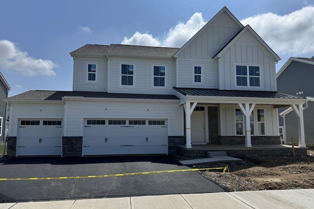 6938 Stillhouse Ln, Dublin, OH 43016 - view of front of home with board and batten siding, a porch, driveway, a garage, and stone siding