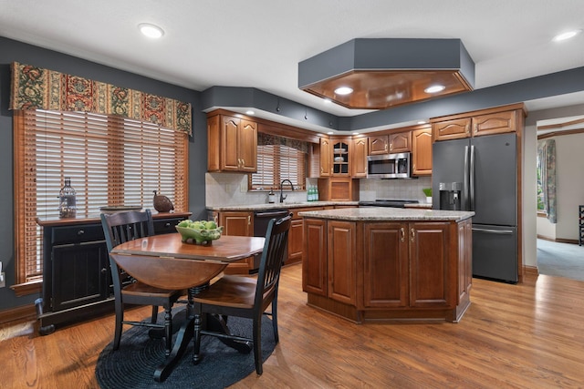 5232 Lola Way, Columbus, OH 43235 - kitchen featuring appliances with stainless steel finishes, decorative backsplash, wood finished floors, a center island, and light stone countertops