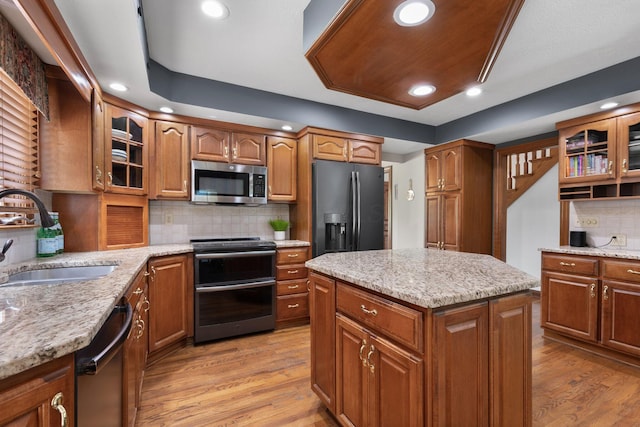 5232 Lola Way, Columbus, OH 43235 - kitchen with stainless steel appliances, light wood-style floors, brown cabinetry, backsplash, and a center island