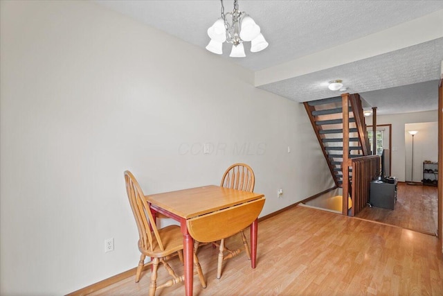 907 Soramill Ln Unit 8E, Columbus, OH 43085 - dining space with a textured ceiling, stairway, a chandelier, and light wood finished floors