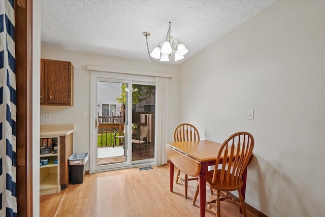 907 Soramill Ln Unit 8E, Columbus, OH 43085 - dining area featuring light wood-style flooring, a chandelier, and a textured ceiling