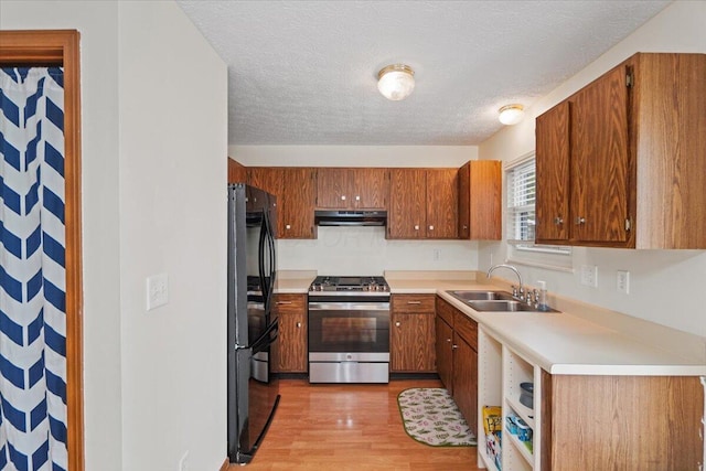 907 Soramill Ln Unit 8E, Columbus, OH 43085 - kitchen featuring gas stove, under cabinet range hood, freestanding refrigerator, light wood-style floors, and brown cabinetry