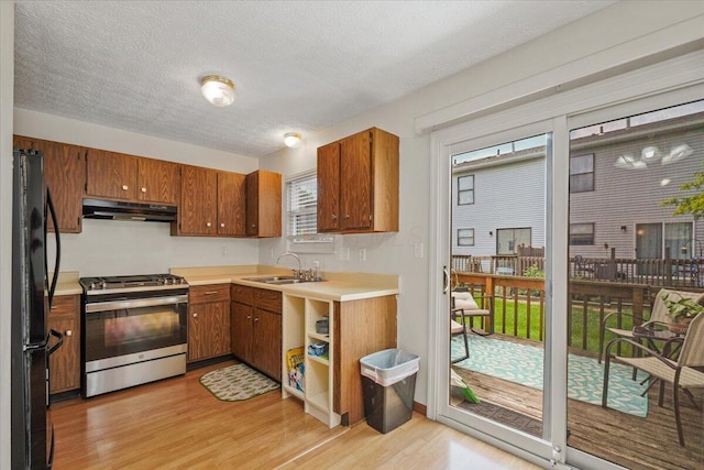 907 Soramill Ln Unit 8E, Columbus, OH 43085 - kitchen featuring gas stove, freestanding refrigerator, under cabinet range hood, light wood finished floors, and brown cabinets