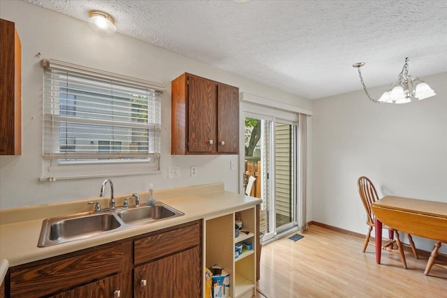 907 Soramill Ln Unit 8E, Columbus, OH 43085 - kitchen with healthy amount of natural light, a chandelier, light wood-type flooring, a textured ceiling, and light countertops