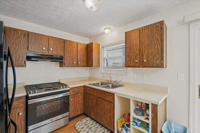 907 Soramill Ln Unit 8E, Columbus, OH 43085 - kitchen featuring gas range, under cabinet range hood, light countertops, brown cabinets, and refrigerator