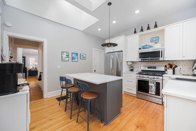133 E Sycamore St, Columbus, OH 43206 - kitchen with appliances with stainless steel finishes, a skylight, a kitchen bar, light wood finished floors, and light countertops