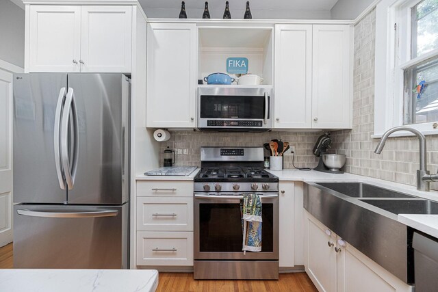 133 E Sycamore St, Columbus, OH 43206 - kitchen featuring stainless steel appliances, decorative backsplash, white cabinets, light wood-style floors, and light stone counters