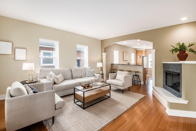 1293 Avondale Ave, Columbus, OH 43212 - living room with light wood-style floors, arched walkways, a fireplace with raised hearth, and recessed lighting