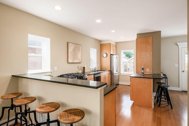 1293 Avondale Ave, Columbus, OH 43212 - kitchen featuring black dishwasher, a peninsula, freestanding refrigerator, a breakfast bar area, and range with gas cooktop