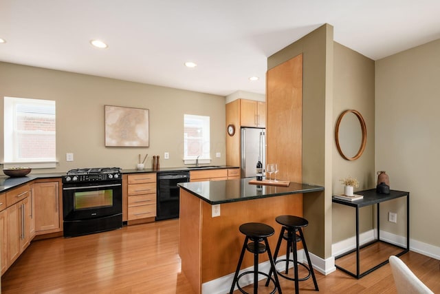 1293 Avondale Ave, Columbus, OH 43212 - kitchen featuring black appliances, dark countertops, light wood finished floors, a breakfast bar, and recessed lighting