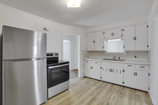 977 Sells Ave, Columbus, OH 43212 - kitchen with appliances with stainless steel finishes, light countertops, tasteful backsplash, light wood-style floors, and white cabinetry