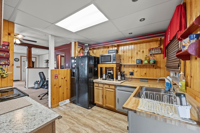 716 Uncapher Ave, Marion, OH 43302 - kitchen with black fridge with ice dispenser, wood walls, dishwasher, stainless steel microwave, and cooktop