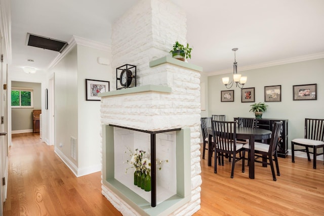 2269 Cranford Rd, Columbus, OH 43221 - dining room featuring a stone fireplace, light wood-type flooring, a chandelier, and crown molding