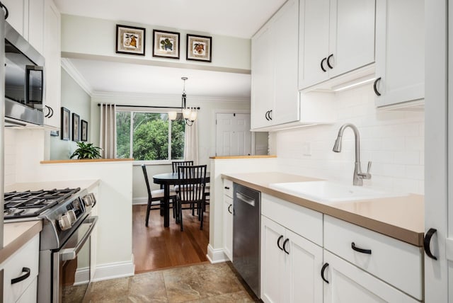 2269 Cranford Rd, Columbus, OH 43221 - kitchen with stainless steel appliances, backsplash, light countertops, white cabinetry, and ornamental molding