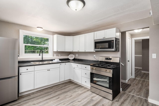 226 N Southampton Ave, Columbus, OH 43204 - kitchen featuring stainless steel appliances, dark countertops, white cabinets, and light wood-style flooring