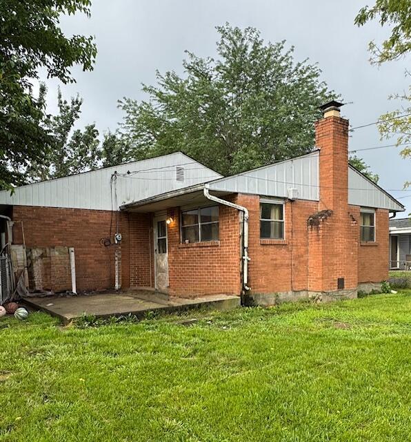 278 Cullman Rd, Columbus, OH 43207 - back of house featuring a lawn, a chimney, a patio area, and brick siding
