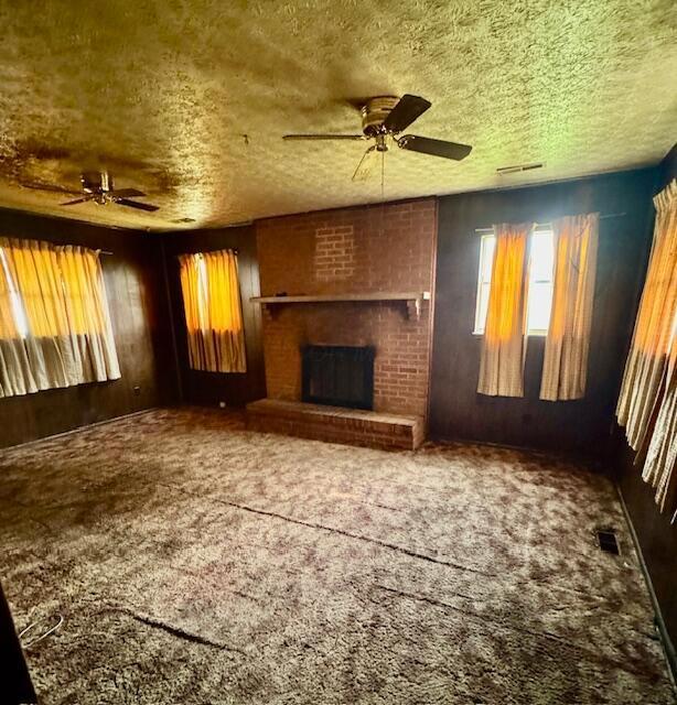 278 Cullman Rd, Columbus, OH 43207 - unfurnished living room featuring a ceiling fan, a textured ceiling, carpet floors, and a brick fireplace