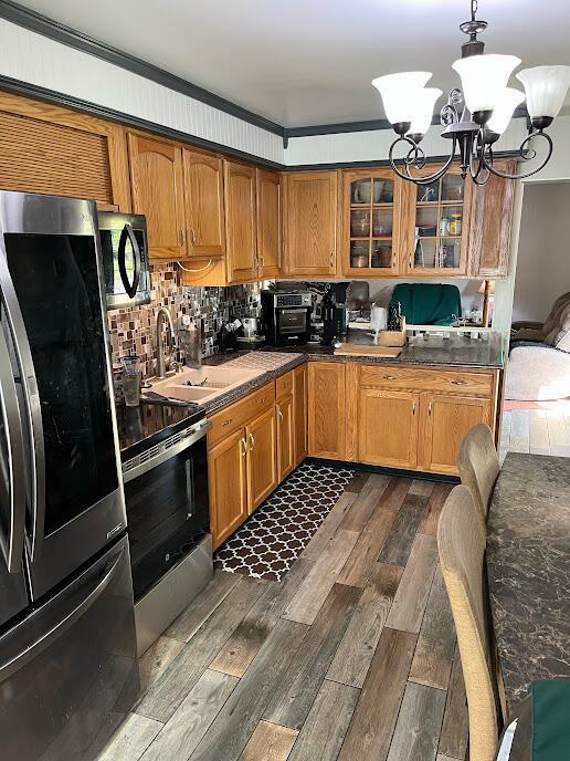 5254 Sedalia Dr, Columbus, OH 43232 - kitchen with appliances with stainless steel finishes, a chandelier, brown cabinets, and glass insert cabinets