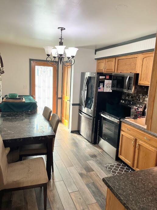 5254 Sedalia Dr, Columbus, OH 43232 - kitchen featuring stainless steel appliances, a chandelier, light wood-type flooring, brown cabinets, and pendant lighting