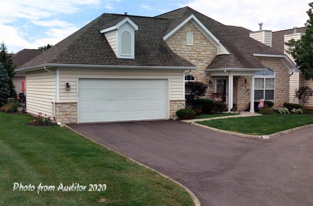 5175 Vinings Grv Unit 5175C, Dublin, OH 43016 - view of front of house with stone siding, driveway, an attached garage, a front yard, and roof with shingles