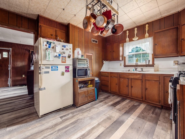775 Koebel Ave, Columbus, OH 43207 - kitchen with freestanding refrigerator, stainless steel microwave, wood walls, brown cabinets, and light countertops