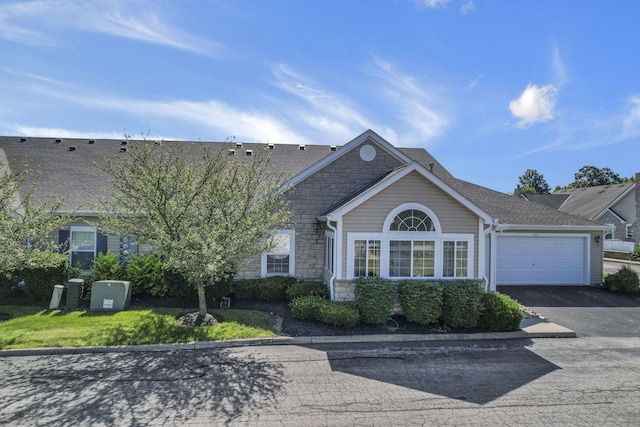 664 Bideford Ave Unit 11B, Blacklick, OH 43004 - view of front facade featuring stone siding, driveway, an attached garage, and roof with shingles