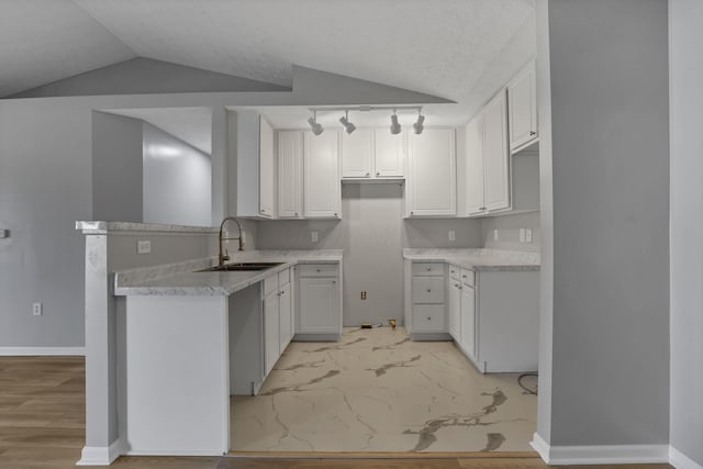 664 Bideford Ave Unit 11B, Blacklick, OH 43004 - kitchen featuring light marble finish flooring, a peninsula, white cabinets, vaulted ceiling, and track lighting