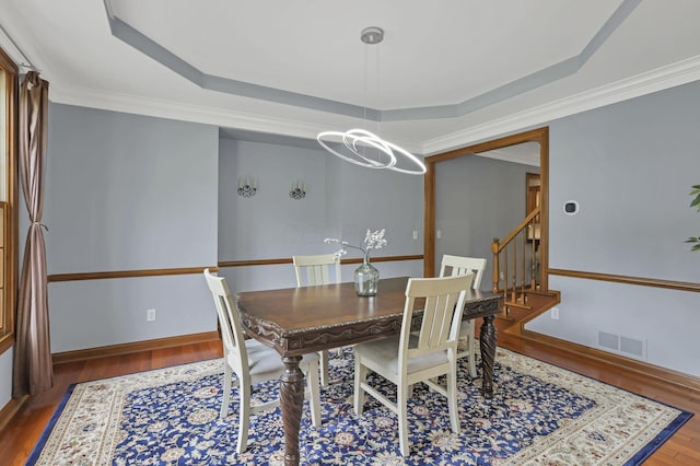 2773 Eleanor Way, Lewis Center, OH 43035 - dining room featuring a raised ceiling, wood finished floors, a chandelier, stairway, and crown molding