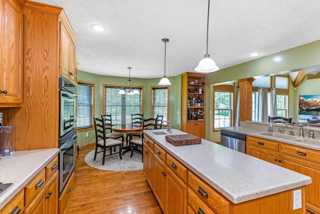 6247 State Route 61, Shelby, OH 44875 - kitchen with dishwasher, a textured ceiling, light wood-style floors, a kitchen island, and light countertops
