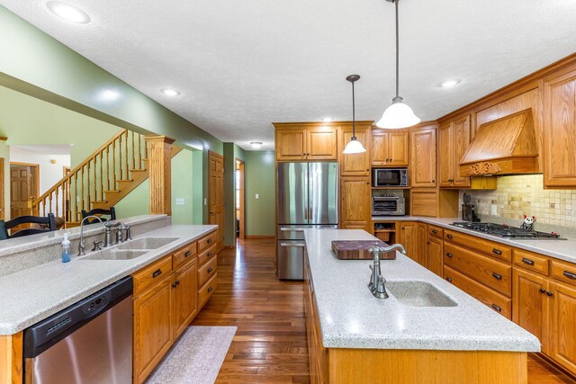 6247 State Route 61, Shelby, OH 44875 - kitchen with appliances with stainless steel finishes, a kitchen island with sink, custom exhaust hood, tasteful backsplash, and dark wood-style floors