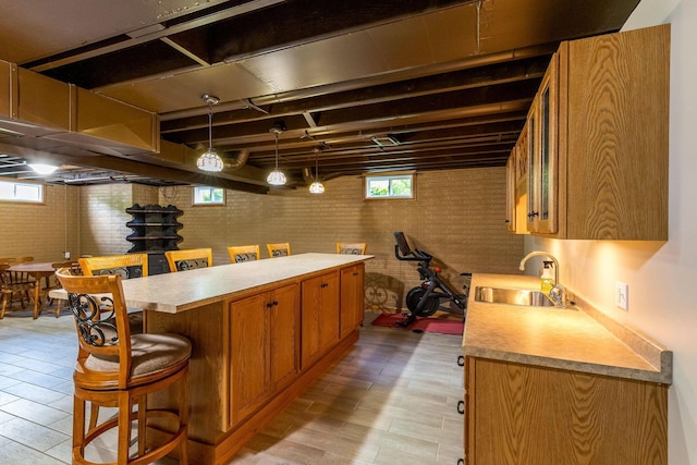 6247 State Route 61, Shelby, OH 44875 - kitchen with a kitchen bar, light countertops, brown cabinetry, light wood-type flooring, and brick wall