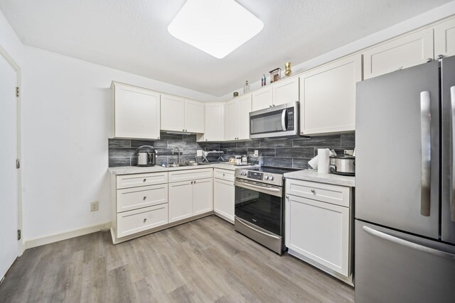 777 Mayme Moore Pl, Columbus, OH 43203 - kitchen featuring appliances with stainless steel finishes, backsplash, light countertops, light wood-style flooring, and white cabinets
