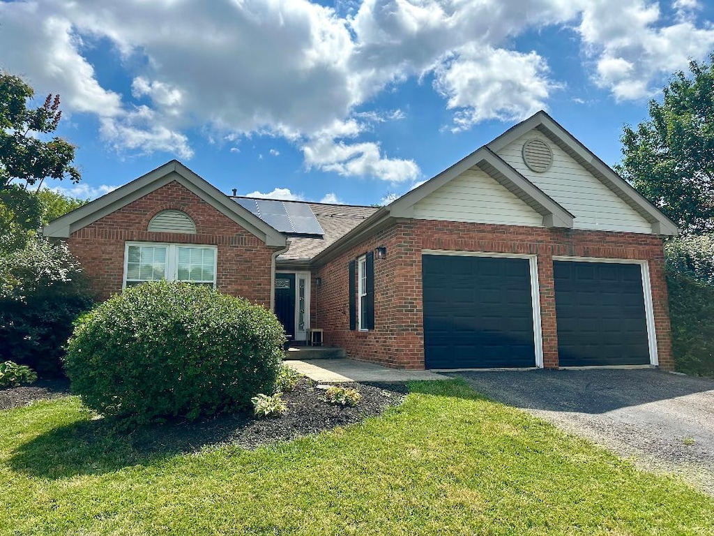 1432 Chenille Way, Galloway, OH 43119 - ranch-style home with brick siding, an attached garage, driveway, solar panels, and a front yard