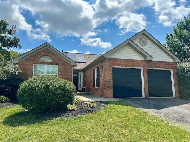 1432 Chenille Way, Galloway, OH 43119 - ranch-style home with brick siding, an attached garage, driveway, solar panels, and a front yard