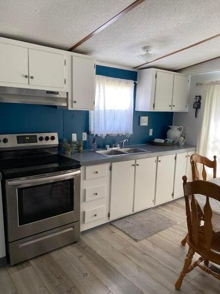1231 Parkway Dr Lot # 26, Logan, OH 43138 - kitchen featuring stainless steel electric range oven, under cabinet range hood, a textured ceiling, light wood-type flooring, and white cabinets