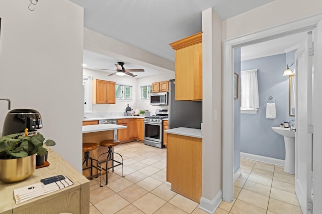 99 E N Broadway St, Columbus, OH 43214 - kitchen with stainless steel appliances, light tile patterned floors, light countertops, and a kitchen bar