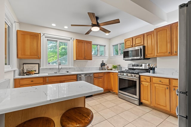99 E N Broadway St, Columbus, OH 43214 - kitchen featuring appliances with stainless steel finishes, a ceiling fan, light tile patterned floors, recessed lighting, and a kitchen breakfast bar