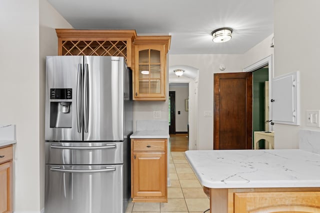 99 E N Broadway St, Columbus, OH 43214 - kitchen with stainless steel refrigerator with ice dispenser, light tile patterned floors, glass insert cabinets, and arched walkways