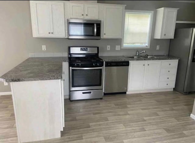 1330 Hanover Rd Unit 507, Delaware, OH 43015 - kitchen with stainless steel appliances, a peninsula, white cabinetry, light wood finished floors, and dark stone counters