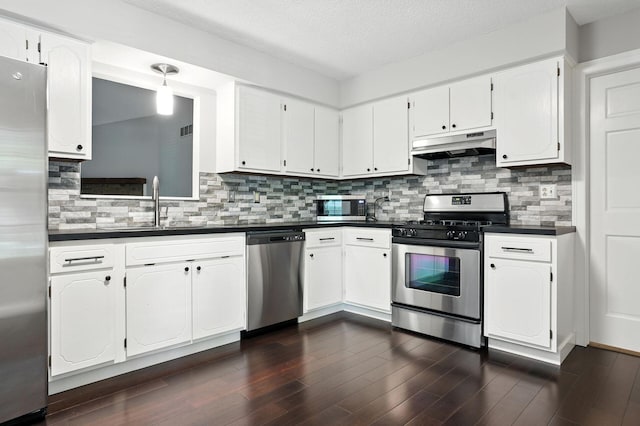5975 Meadowsglen Dr, Dublin, OH 43017 - kitchen featuring appliances with stainless steel finishes, under cabinet range hood, dark countertops, dark wood finished floors, and white cabinets