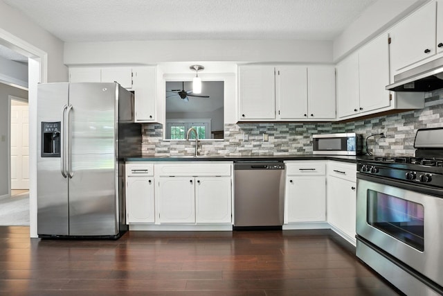 5975 Meadowsglen Dr, Dublin, OH 43017 - kitchen featuring appliances with stainless steel finishes, under cabinet range hood, dark countertops, ceiling fan, and dark wood-style floors