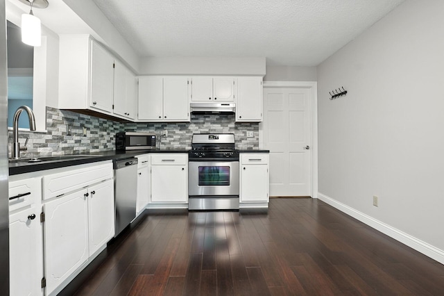 5975 Meadowsglen Dr, Dublin, OH 43017 - kitchen with stainless steel appliances, dark countertops, under cabinet range hood, backsplash, and white cabinetry