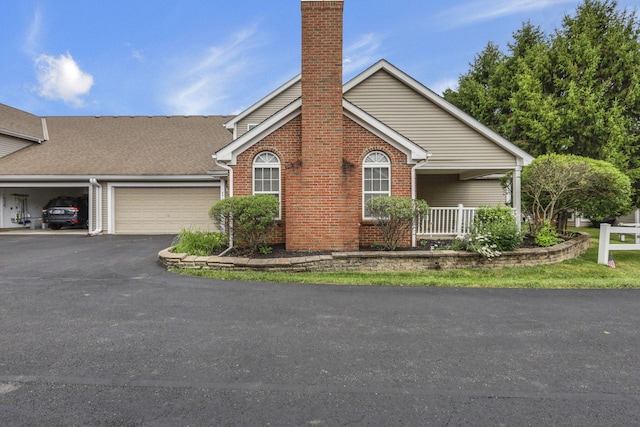 892 Shelbourne Pl, Newark, OH 43055 - view of front facade with brick siding, a chimney, an attached garage, asphalt driveway, and a porch