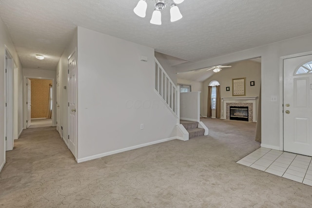 892 Shelbourne Pl, Newark, OH 43055 - unfurnished living room with ceiling fan, light carpet, a tiled fireplace, stairs, and a textured ceiling