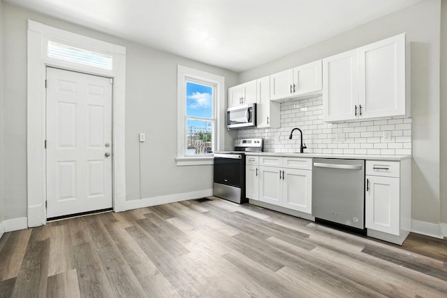 538 W Town St, Columbus, OH 43215 - kitchen featuring stainless steel appliances, decorative backsplash, white cabinetry, light countertops, and light wood finished floors