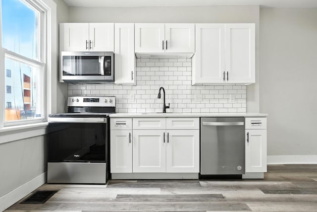 538 W Town St, Columbus, OH 43215 - kitchen with stainless steel appliances, backsplash, light countertops, and white cabinetry
