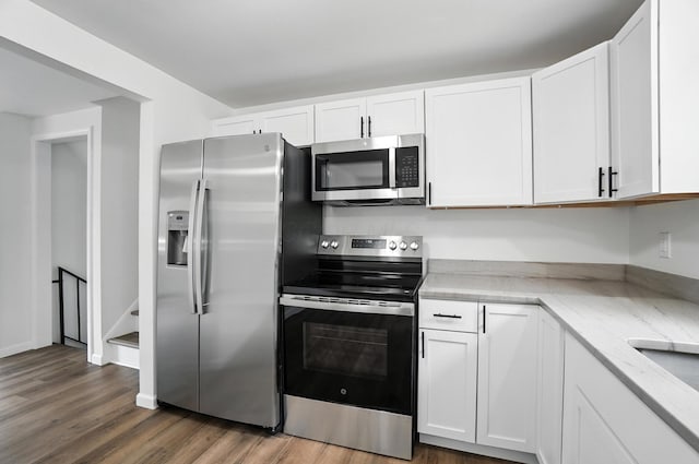 5244 Refugee Rd, Columbus, OH 43232 - kitchen featuring appliances with stainless steel finishes, white cabinetry, wood finished floors, and light stone counters