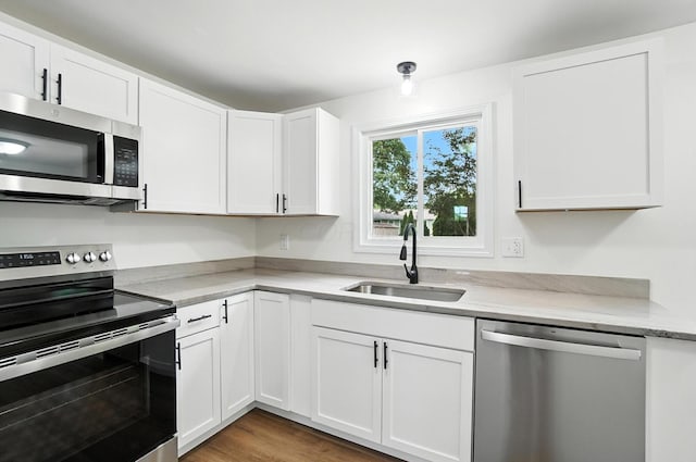 5244 Refugee Rd, Columbus, OH 43232 - kitchen with appliances with stainless steel finishes, white cabinetry, light stone countertops, and wood finished floors